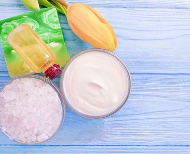 ahşap arka planda kozmetik krem, sabun, tuz, lale çiçeği