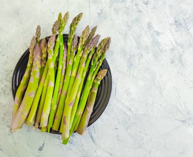 gri beton arka plan üzerinde bir plaka üzerinde taze kuşkonmaz