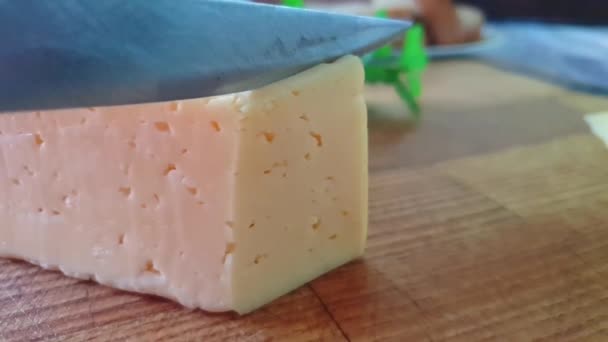 Ahşap Bir Arka Plan Üzerinde Bir Bıçak Ile Kesilmiş Peynir — Stok video