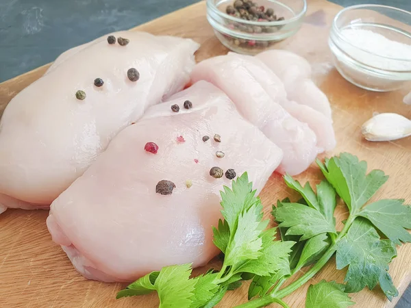 fresh chicken breast, parsley on a concrete background