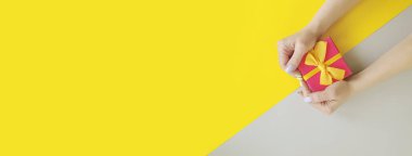 kadın el renkli bir arka plan üzerinde bir hediye kutusu tutar