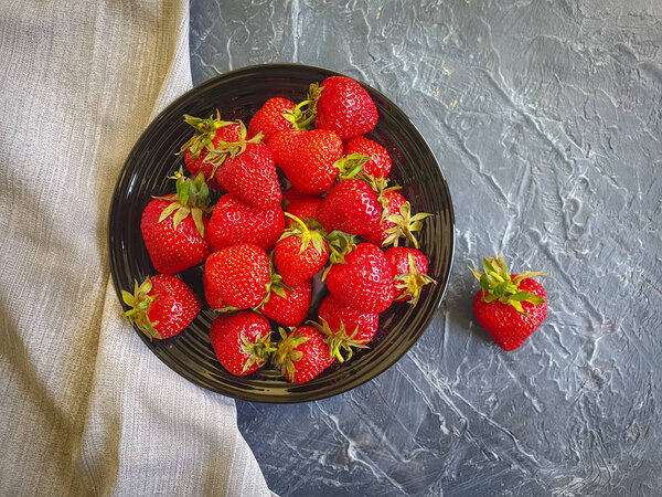 fresh strawberries in a plate on a concrete background