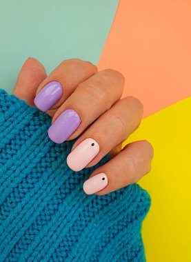 Kadın eli rengarenk arka planda güzel bir manikür.
