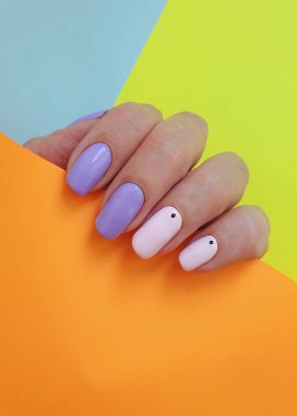 Kadın eli rengarenk arka planda güzel bir manikür.