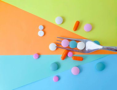 çatal renkli haplar renkli arka planda vitaminler