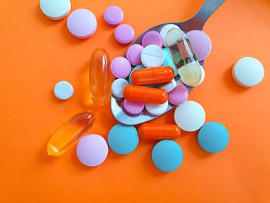 Renkli arka planda kaşık hapları vitaminleri