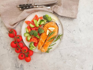 Tabakta kızarmış somon, çimentoda domates.