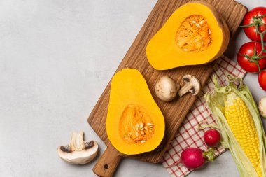 Gri arka planda balkabağı, mısır, mantar ve renkli yapraklarla taze sonbahar hasadı.