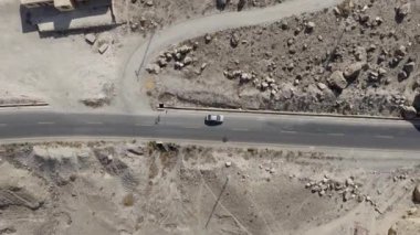 Aerial view of a solitary car journeying through a rugged, rocky terrain in Pakistan.