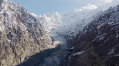 Aerial view of a majestic glacier nestled between towering snow-covered mountains in Pakistan.
