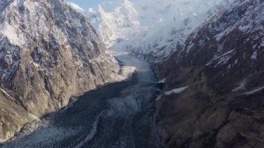 Aerial view of a majestic glacier nestled between towering snow-capped mountains in Pakistan, highlighting the raw beauty of the Himalayan landscape.