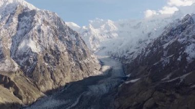 Aerial view of a majestic glacier nestled between towering snow-covered mountains in Pakistan.