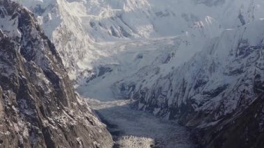 A breathtaking aerial view of a glacier nestled between towering snow-covered mountains in Pakistan.
