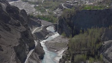 Aerial View of a River Valley in Pakistan, Highlighting Traditional Architecture and Lush Greenery Amidst Rocky Mountains.