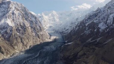 Aerial view of a majestic glacier nestled between towering snow-peaked mountains in Pakistan.