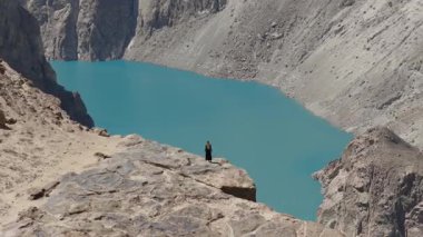 Aerial view of a breathtaking turquoise lake nestled in the mountains of Pakistan, highlighting the stark contrast between the vibrant water and rugged terrain.