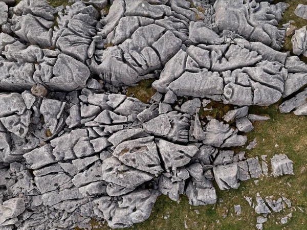 Havadan bakıldığında, doğal bir manzarada çimen parçalarıyla karışık kireçtaşı kaldırım desenleri sergileniyor..
