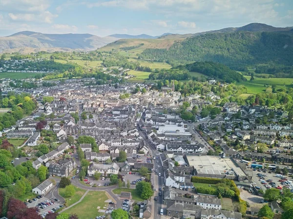 Yuvarlanan tepelerin arasına yerleşmiş, parlak bir gökyüzünün altında canlı bir manzara gösteren tuhaf bir kasabanın havadan görünüşü..