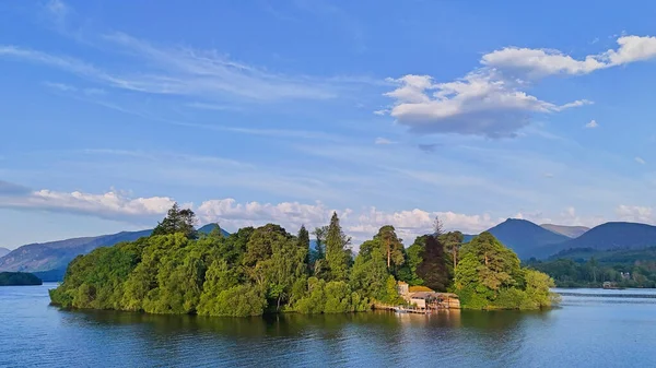 Bereketli ağaçlarla kaplı resim gibi bir ada berrak mavi bir gökyüzünün altında sakin bir gölde huzur içinde duruyor..