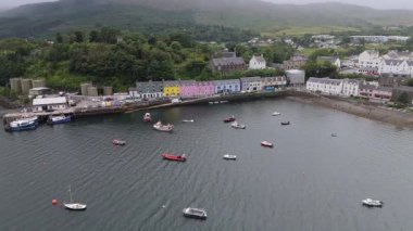 Portree 'nin Skye Adası' ndaki insansız hava aracı görüntüleri rıhtımdaki renkli binalar ve denizde tekneler. Bu görüntü İskoçya 'nın Skye Adası' ndaki Portree 'nin resimli görüntüsünü çeker. Canlı binalar rıhtım boyunca uzanıyor..