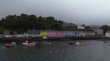 Renkli evlerin insansız hava aracı görüntüleri güzel bir İskoç kasabasının rıhtımında. İskoçya 'nın Skye Adası' nın renkli bir köyü olan Portree 'nin havadan görünüşünde liman boyunca parlak boyalı binalar, tekneler ve tarihi bir kilise bulunuyor..