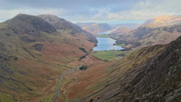 Warnscale 'in panoramik manzarası bulutlu bir gökyüzünün altında sakin bir gölü ve dolambaçlı bir nehri gösteren çarpıcı bir dağ silsilesi..