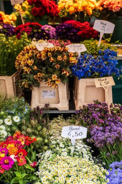 Freiburgs açık hava pazarındaki renkli meyve ve sebze tezgahlarında canlı yerel bir ortamda taze mevsimlik ürünler ve canlı renkler sergileniyor..