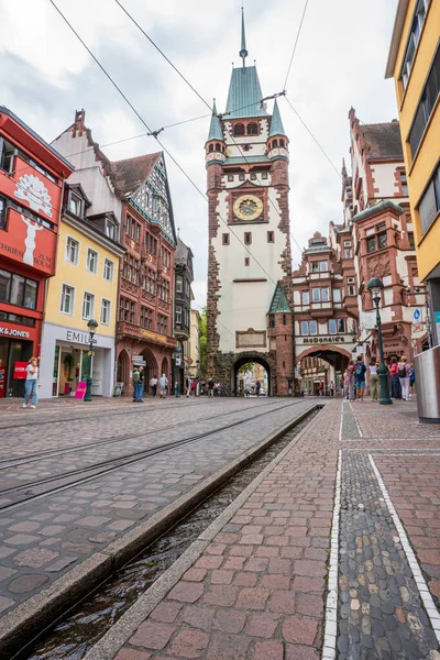 Freiburgs Martinstor 'da sakin bir sabah sahnesi, ikonik kule, tramvay hattı ve hayat dolu eski kasaba atmosferi..