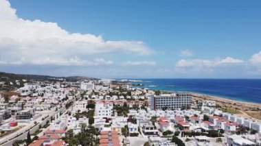 Kıbrıs 'ın beyaz evleri, kırmızı çatıları ve deniz ufkuyla kıyı kentinin insansız hava aracı görüntüsü. Akdeniz tatil köyü Paralimni, Mavi gökyüzü ve deniz manzaralı Protaras. 