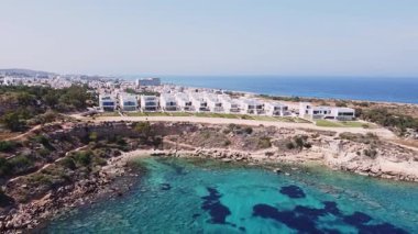 Lüks Akdeniz gayrimenkullerinin deniz manzaralı insansız hava görüntüsü. Kıbrıs 'ta modern beyaz villalar ve evler. Lüks tatil köyü. 