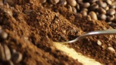 Kaşık, kahve çekirdeğine karşı öğütülmüş kahveyi topluyor. Yüksek kaliteli FullHD görüntüler