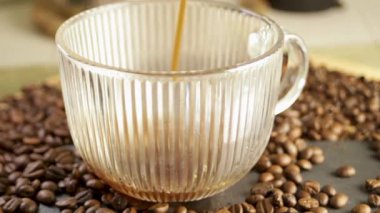 Kahve fincanın içine kahve çekirdeğinin arka planına dökülüyor. Sıcak içecekten buhar çıkıyor. Yakın plan. Yüksek kaliteli FullHD görüntüler