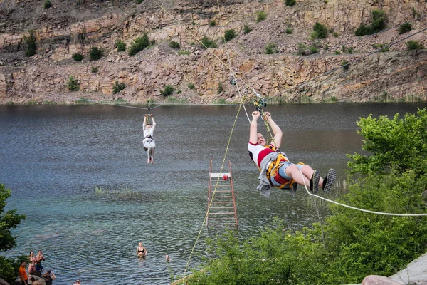 Ukrayna, Migea - 30 Temmuz 2018: Zipline. Çelik kablo ekipman slaytlarda adam. Arabası parça göl üzerinde. Aşırı ve aktif dinlenme.