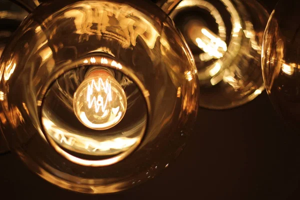 Classic edison bulb in a transparent glass ceiling on a black background — Stock Photo, Image