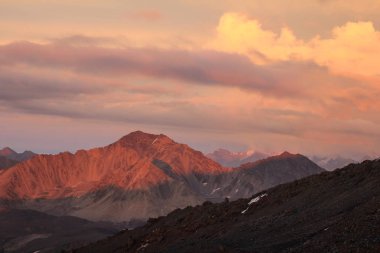Batan güneşin ışınları dağ aralıklardaki görünümünü. Ana kamp Elbrus kuzey yamacında.