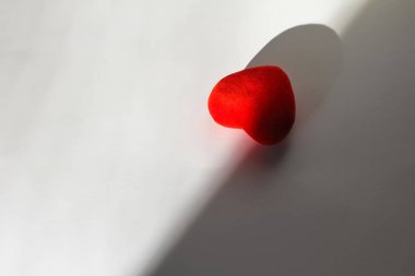 Güneş ışınları ve gölge beyaz bir arka plan üzerinde dekoratif kırmızı kalp. Senin metin için yer 