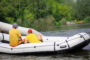 Nehrin ortasında beyaz bir teknede iki öğretim elemanları kadar sallar, turistik, aşırı ve eğlenceli spor pompalanır. Pivdennyi Buh nehirde rafting