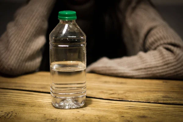 少女は 彼女の手でテーブルの上の水のボトルを保持します 健康的なライフ スタイルのためのきれいな水 — ストック写真
