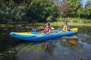 Mygiya / Ukrayna - 22 Temmuz 2018: mutlu genç kaç hayat yelekler içinde gülümseyen bir kayık yelken. Güney Bug Nehri rafting