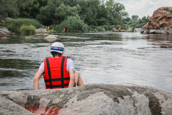 孤独的男人穿着红色背心和安全帽坐在河边 — 图库照片