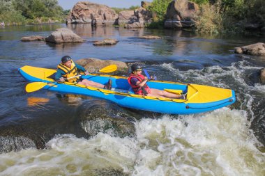 Mygiya / Ukrayna - 22 Temmuz 2018: mutlu genç kaç hayat yelekler içinde gülümseyen bir kayık yelken. Güney Bug Nehri rafting