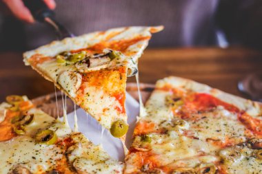 Yakın çekim. Vejetaryen pizza mantar, peynir ve zeytin, kesme ile karanlık bir arka plan üzerinde