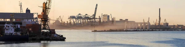 The tugboat is at the pier in the port. Panoramic view of the evening port