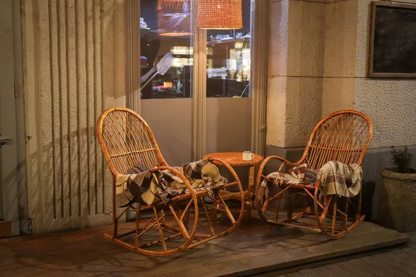 Café rustique sur le trottoir avec tables en bois, pot de fleurs et tresses sur chaise en osier à l'extérieur — Photo