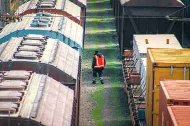 Bir çekiç ile tulum demiryolu işçisi eski yük vagonu inceler. trenler kargo terminalinde yükleme için sırada bekliyor. demiryolu taşımacılığı için en ekonomik lojistik çözümleri