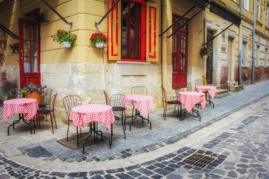 Eski şehirde açık hava kafesi. Dar eski sokakta yaz kafe. Evler arasında dar döşeli sokakta vintage tablolar ve Lviv duvarlar arasında, Ukrayna. Kavram - seyahat, simgesel yapılar, bir anıt