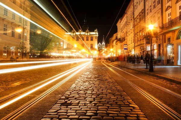 Geceleri Lviv panoraması. Avrupa ortaçağ kentinin gece sokak görünümü. Geceleri Lviv Market meydanı. Konsept - seyahat, yerler. Tramvaydan donmuş ışık. Uzun pozlama