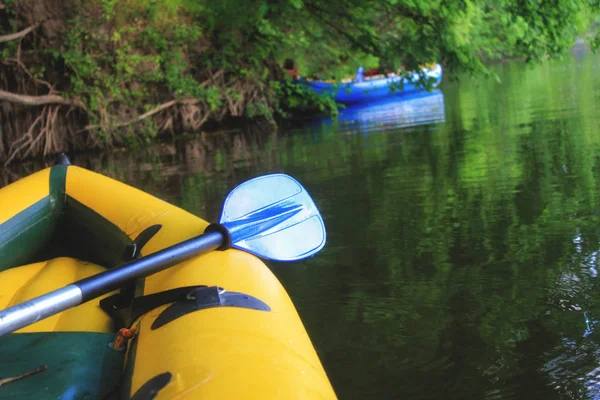多瑙河平静的水面上,黄船的鼻梁和蓝色的桨. 山区和森林构成背景 — 图库照片
