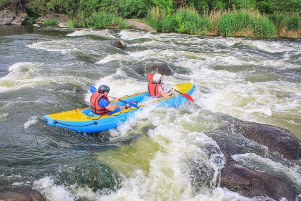 Young couple enjoy white water kayaking on the river, extreme and fun sport at tourist attraction. Rafting on the  Pivdennyi Buh River. Active adventure couple along the river