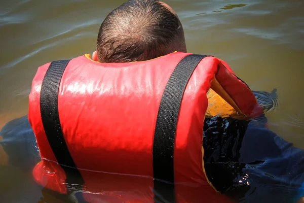 Um homem com um colete vermelho na água. Visão traseira close-up . — Fotografia de Stock
